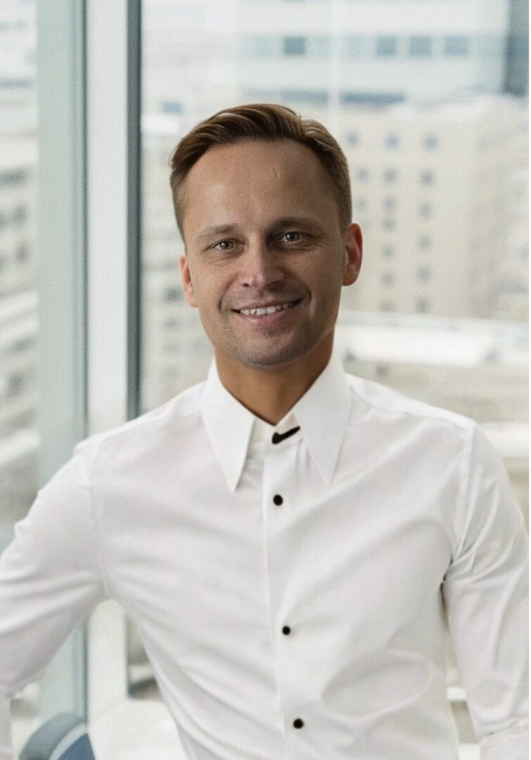 na zdjęciu jest uśmiechnięty mężczyzna w białej koszuli